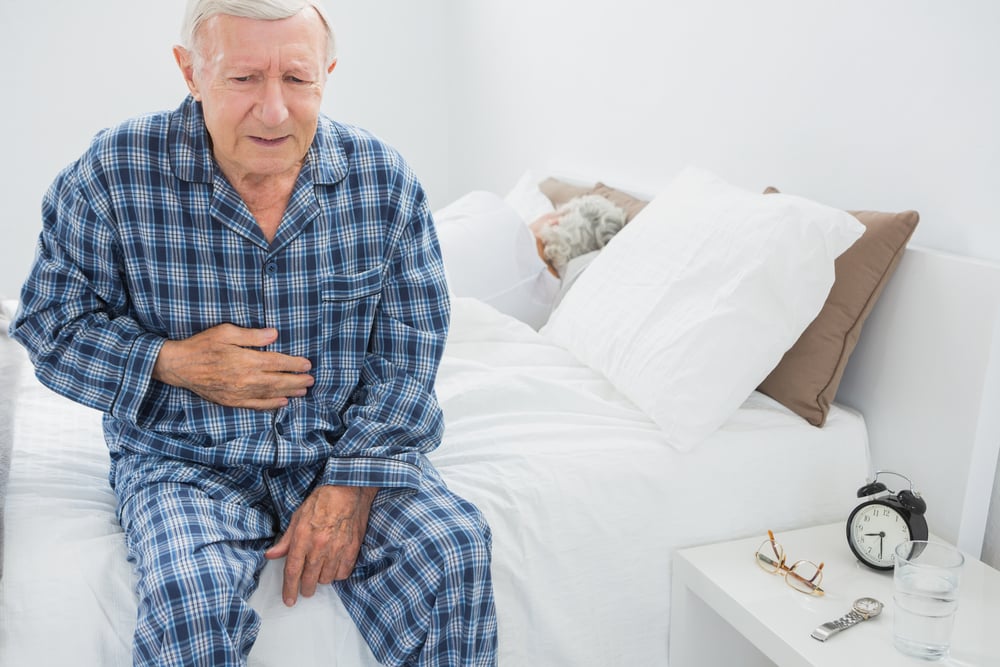 Elderly man suffering with belly pain in the bedroom