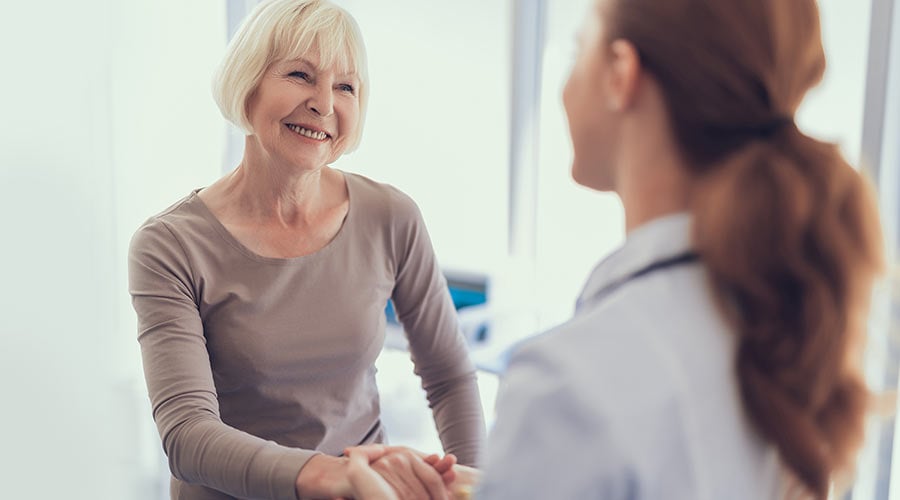 Smiling woman shakes hands with her doctor