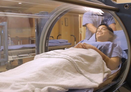 Woman being rolled into a hyperbaric oxygen chamber