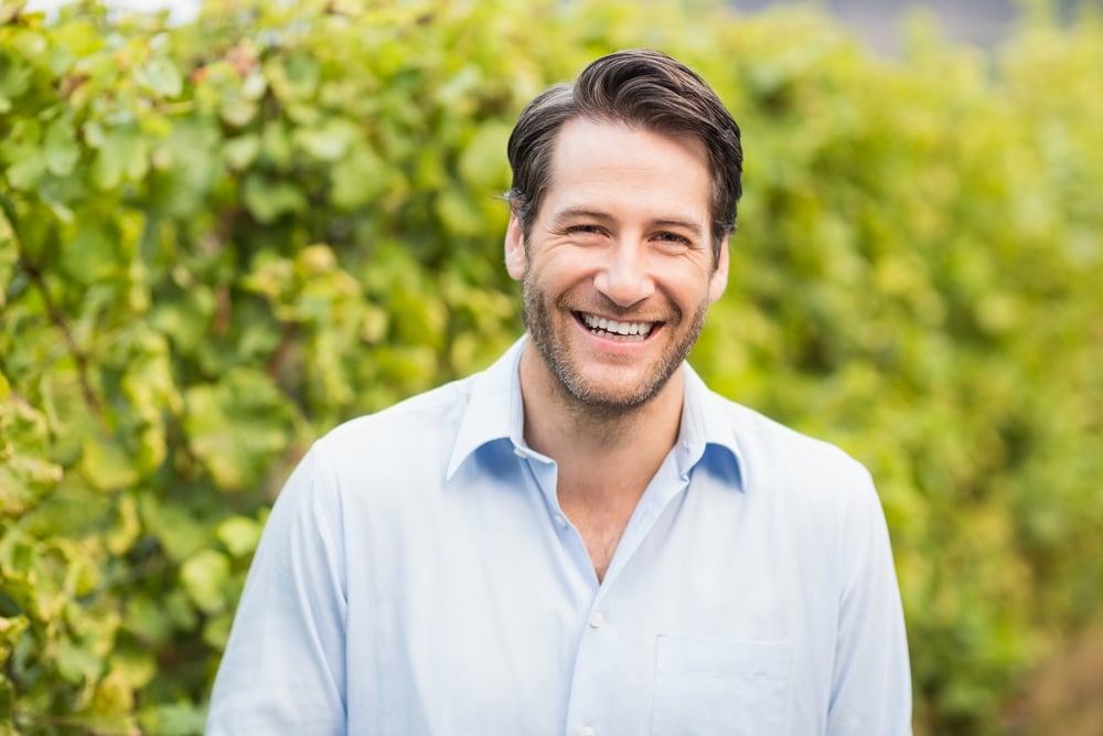 Young happy man smiling at camera in the grape fields