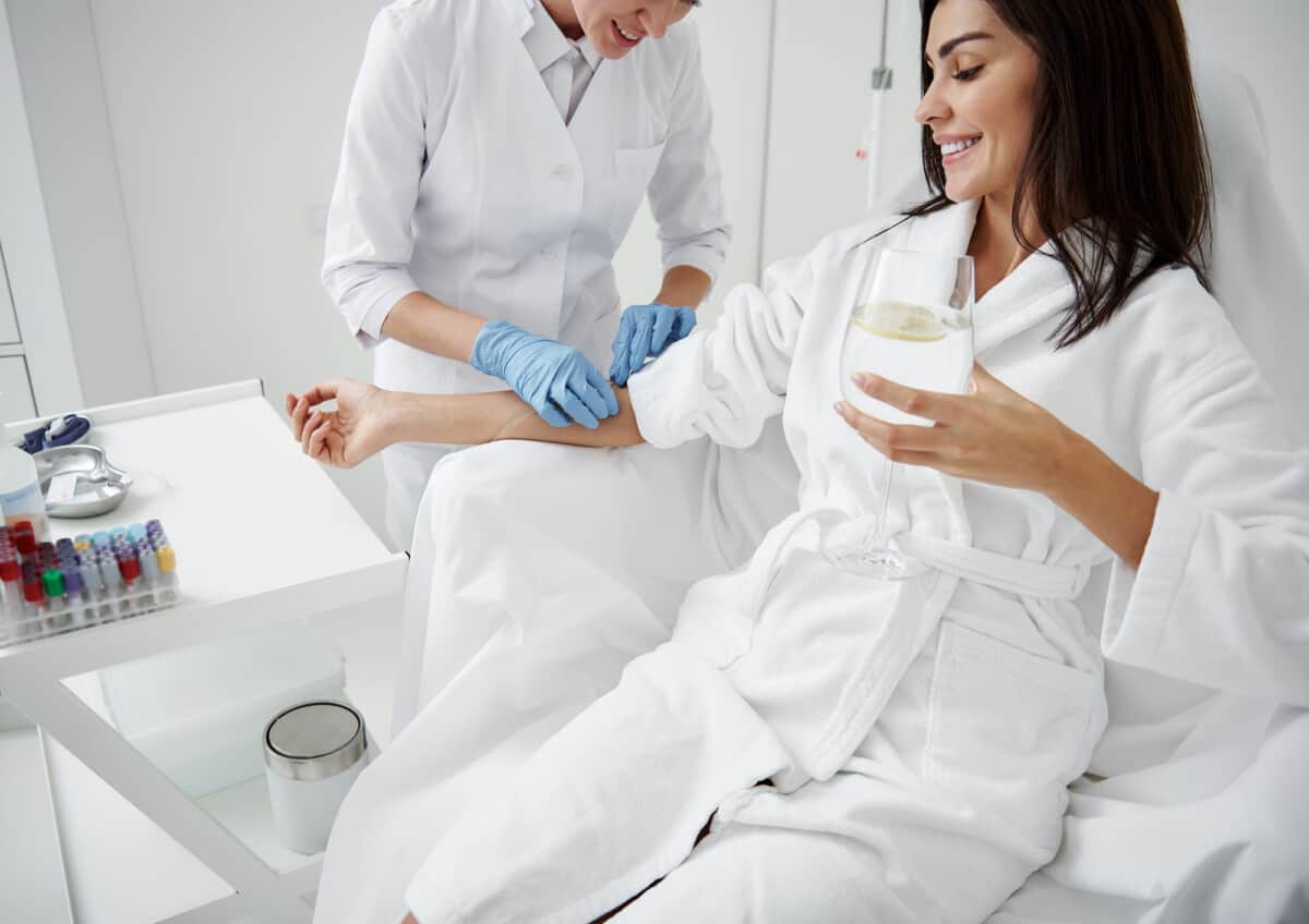 Woman getting IV Therapy while relaxing and drinking lemon water