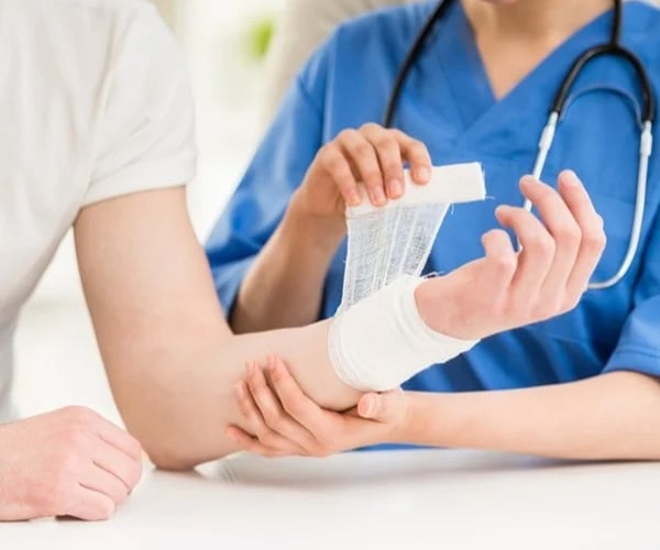 a closeup of a doctor applying a bandage to a persons forearm