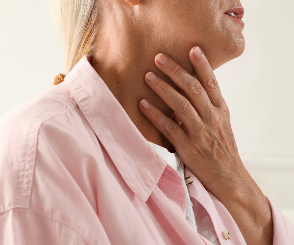 A close up of a person holding their neck with their left hand.