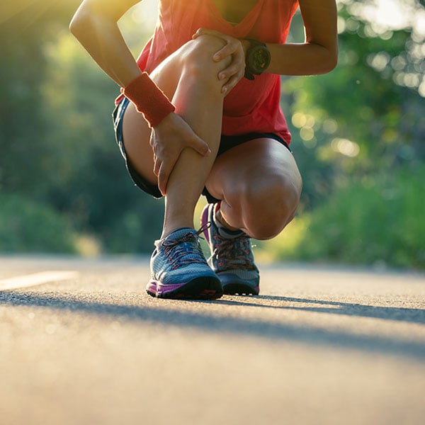 runner dealing with ankle injury on trail